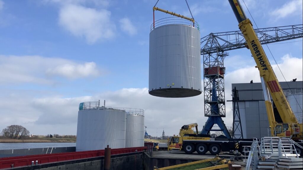 Drei Edelstahl-Lagertanks auf einem Schiff verladen, bereit zur Auslieferung an den Kunden, mit Fokus auf industrielle Logistik und Transport.
